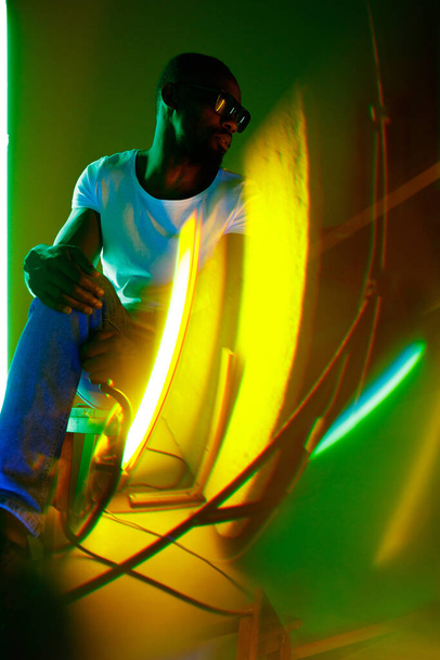 Cinematic portrait of handsome young man in neon lighted room, stylish musician - Photo, image