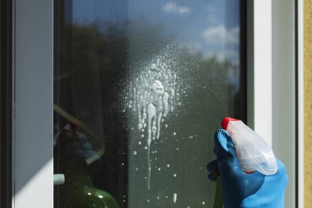 Window cleaning with a scraper and window cleaner. Cleaning in a house or apartment. Removing dirt from windows and windows - Photo, Image