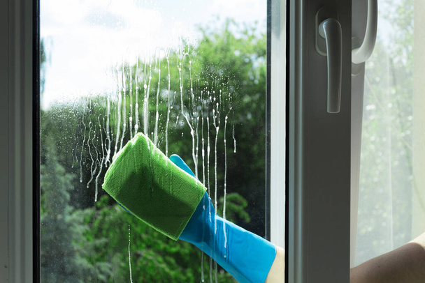 Nettoyage des vitres avec un racleur et un nettoyant pour vitres. Nettoyage dans une maison ou un appartement. Enlever la saleté des fenêtres et fenêtres - Photo, image