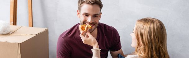 panoramisch concept van vrouw voeden vriendje met smakelijke pizza - Foto, afbeelding