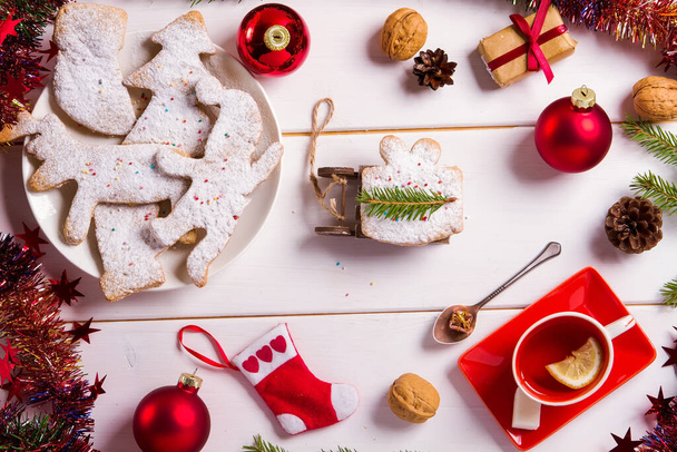 Різдвяний та новорічний фон з печивом та чаєм, червоними тонами Різдвяні іграшки, мішура, горіхи та шишки, святкова атмосфера та чайна вечірка з сім'єю
 - Фото, зображення