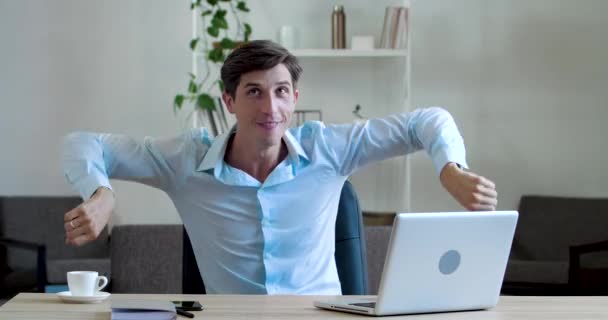 Aktivní mladý obchodní manažer dělá cvičení v kanceláři sedí u stolu, aktivně pohybuje rukama, točí rukama, tančí v práci během přestávky baví, dělá gymnastiku pro mužské tělo - Záběry, video