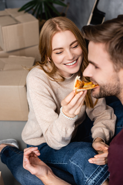 selective focus of joyful woman feeding bearded man with pizza - Photo, Image