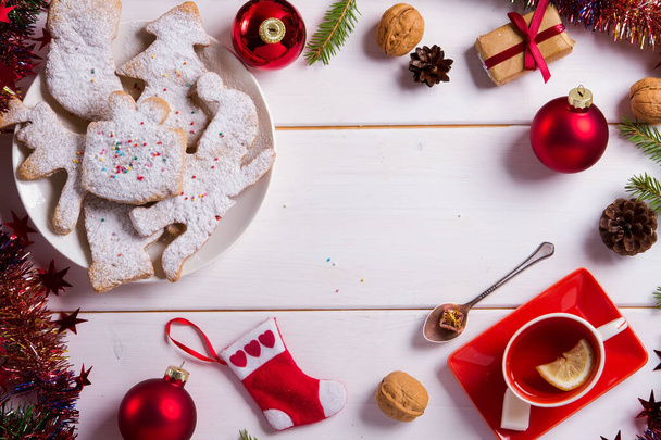 クリスマスのお菓子プレートにクッキーを焼く。クリスマスクッキーのために飾られ、クリスマスバンプ。お茶を飲んで。新年の食べ物。赤い装飾だ。トップ表示 - 写真・画像