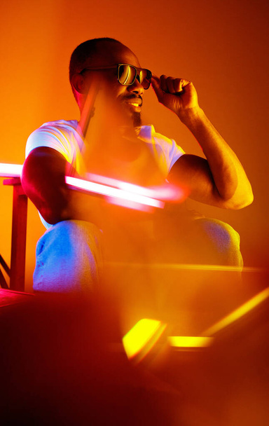 Cinematic portrait of handsome young man in neon lighted room, stylish musician - 写真・画像