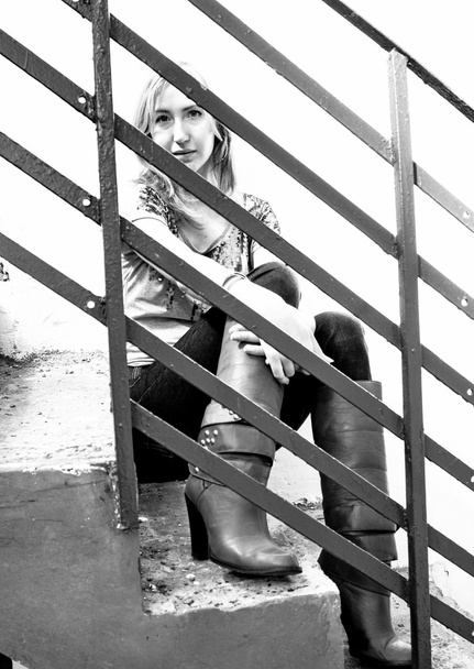 Retrato de adolescente sentada en escaleras detrás de barandillas metálicas
 - Foto, imagen