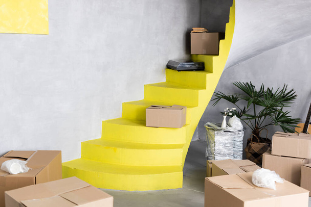 boîtes en carton sur les escaliers jaunes dans un nouvel appartement, concept de déménagement - Photo, image