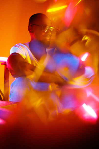 Cinematic portrait of handsome young man in neon lighted room, stylish musician - Foto, Bild