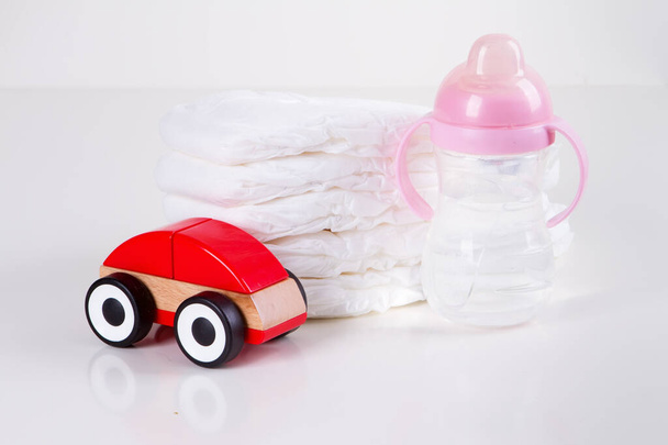 Stapel van baby wegwerp luiers en speelgoed over witte achtergrond - Foto, afbeelding