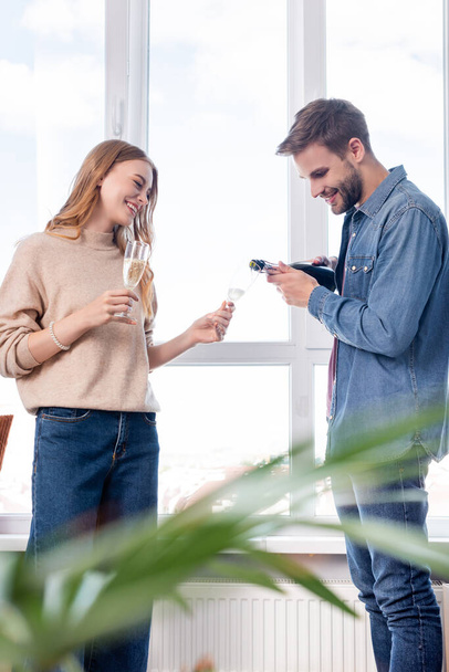 selective focus of man pouring champagne in glass of joyful girlfriend  - Photo, Image