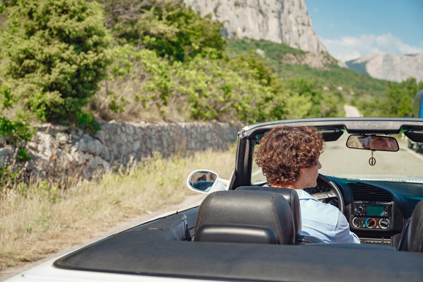Couple enjoying a drive in a convertible in summer road. Friends going on holidays. Italian vacation serpentine roads, a redheaded woman and a beautiful young man - Foto, immagini
