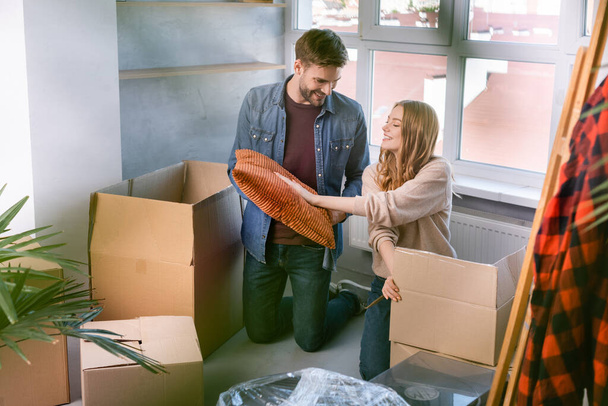 selective focus of man and woman touching pillow unpacking carton boxes in new home, moving concept - Photo, Image