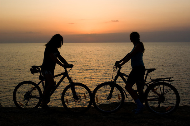 ζευγάρι με ποδήλατα, βλέποντας το ηλιοβασίλεμα. - Φωτογραφία, εικόνα