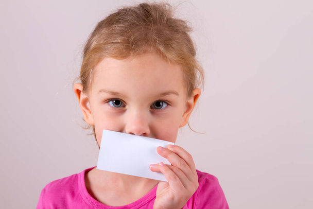 menina criança segurando cartão na frente lábios - Foto, Imagem