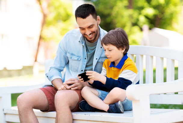 father and son with smartphone at park - Foto, Imagen