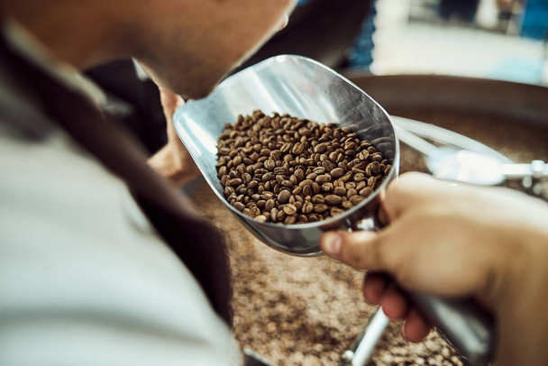 Young man smelling freshly roasted coffee beans - Photo, Image