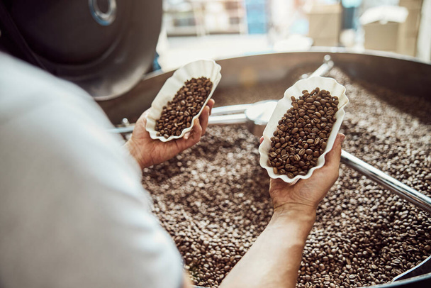 Mladý muž kontroluje kvalitu čerstvě pražených kávových zrn - Fotografie, Obrázek