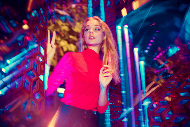 Cinematic portrait of handsome young woman in neon lighted room, stylish musician - Fotografie, Obrázek