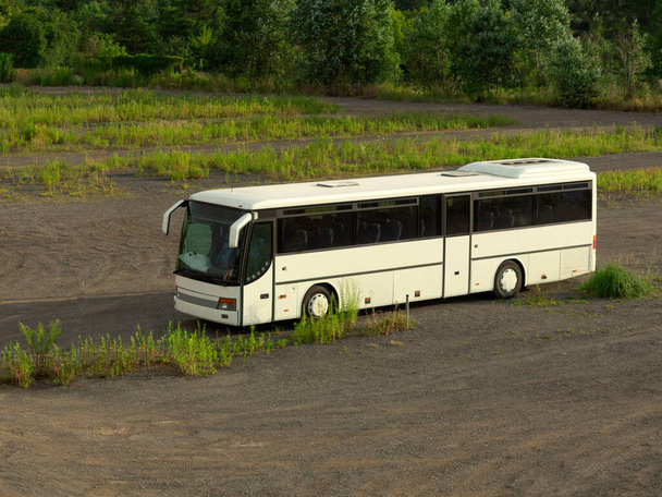  Bílý autobus stojí sám v poli Velký bílý autobus na parkovišti. Jeden autobus na velkém parkovišti - Fotografie, Obrázek
