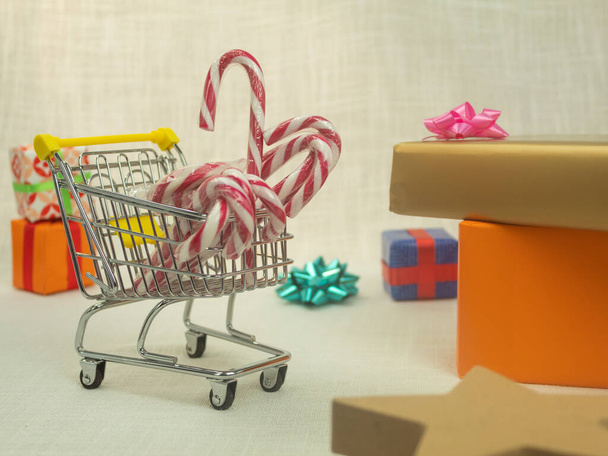 Navidad piruletas multicolores y regalos. Piruletas en una canasta y regalos de Navidad. Carro y regalos, cesta llena de regalos - Foto, imagen