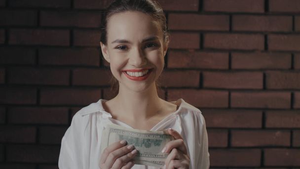 Весела ділова жінка рахує гроші для вигідних інвестицій на цегляну стіну
 - Фото, зображення