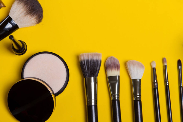 brosse de maquillage et cosmétiques, sur fond jaune isolé à plat - Photo, image