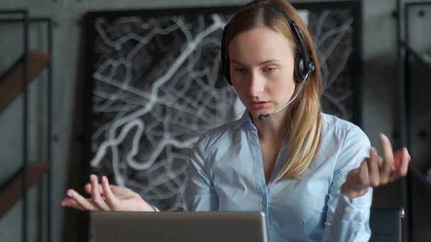 Happy female manager wearing wireless headphones, looking at laptop screen, holding pleasant conversation with partners clients online, working remotely at workplace - Photo, Image