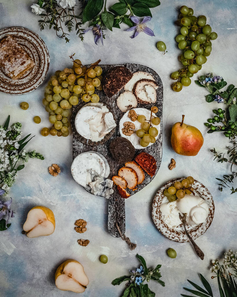 plate with set of cheese and grape with pears and flowers on grunge background - Foto, Bild