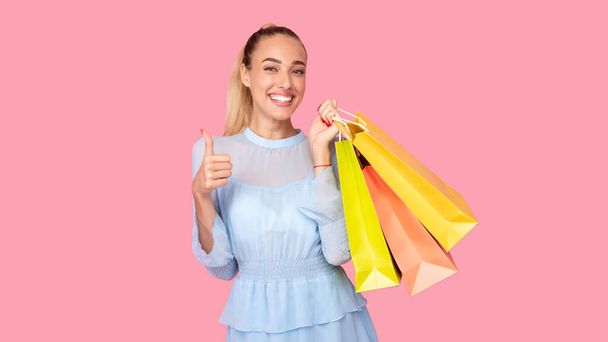 Young lady holding shopping bags showing thumbs up - Foto, Imagem