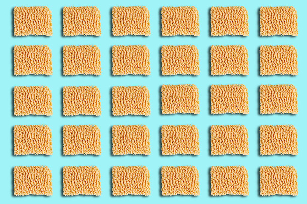 Pattern with a briquette of instant noodles on a blue background. The view from the top. - Photo, Image