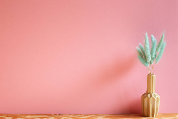 Vaso di erba verde coda lepri (Lagurus ovatus) fiori secchi su tavolo di legno con sfondo rosa - Foto, immagini