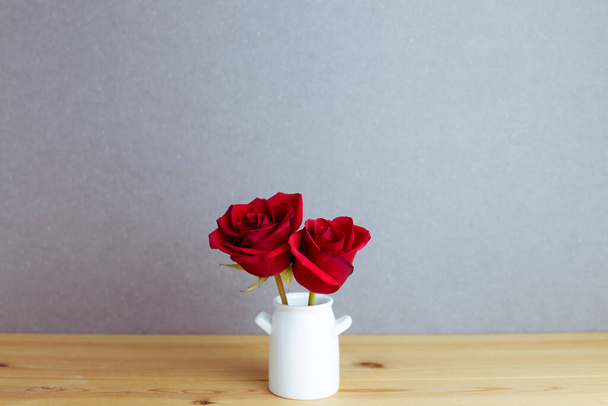 Rode roos bloemen in vaas op houten tafel met grijze achtergrond. bloemstuk, kopieerruimte - Foto, afbeelding