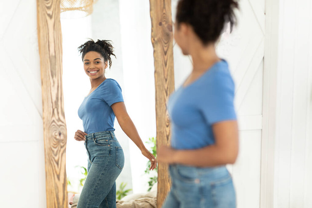 Gioioso afro-americano ragazza dopo il dimagrimento guardando nello specchio in casa - Foto, immagini