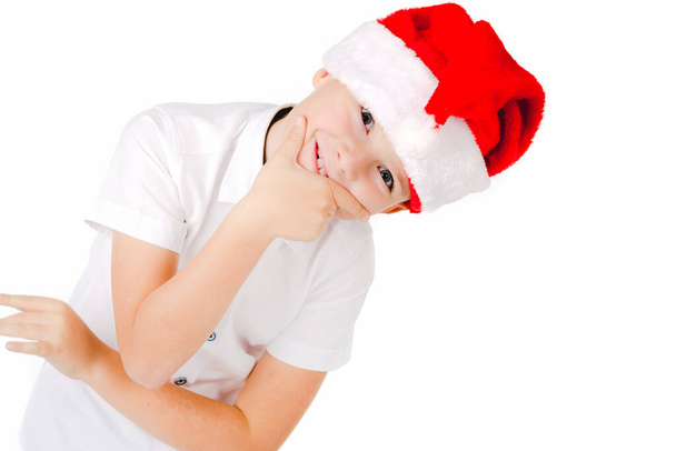Criança adorável com chapéu vermelho de Natal em um fundo sobre branco ele é bonito e pensativo - Foto, Imagem