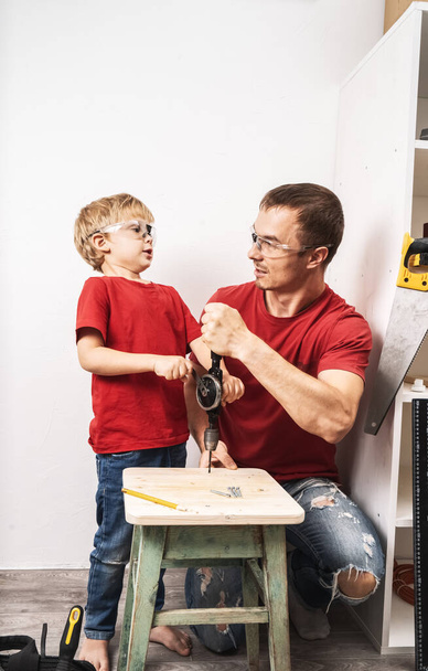 Father teaches son to work with a hand drill. - Fotoğraf, Görsel
