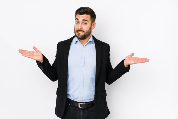 Young caucasian business man against a white background isolated confused and doubtful shrugging shoulders to hold a copy space. - Photo, Image