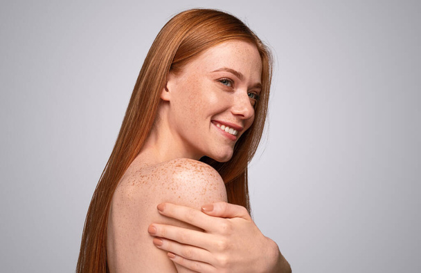 Happy freckled woman touching shoulders - Foto, afbeelding