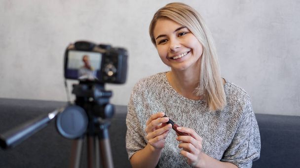 Vlogger female showing lipstick. Beauty blogger in home studio - Фото, зображення