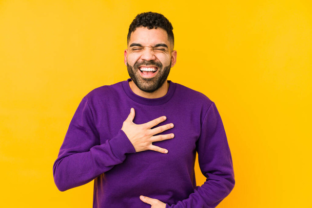Young mixed race arabic man isolated laughs happily and has fun keeping hands on stomach. - Fotoğraf, Görsel