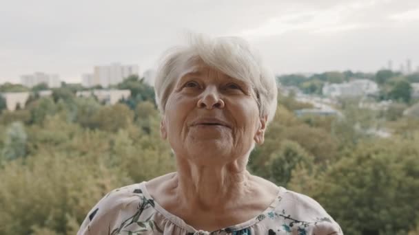 ηλικιωμένη γυναίκα που εξασκείται στην αναπνοή στη βεράντα. έννοια της υγειονομικής περίθαλψης και ευημερίας - Πλάνα, βίντεο