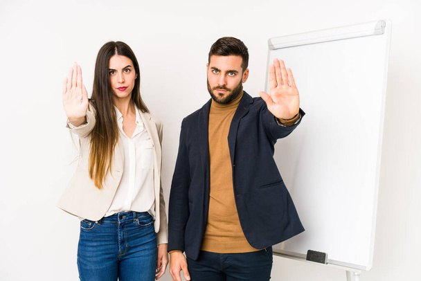 Young caucasian business couple isolated standing with outstretched hand showing stop sign, preventing you. - Φωτογραφία, εικόνα