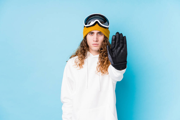 Jovem caucasiano vestindo uma roupa de esqui isolado de pé com a mão estendida mostrando sinal de parada, impedindo-o. - Foto, Imagem