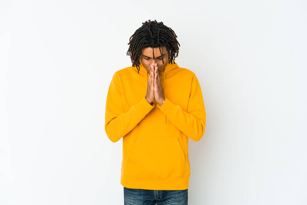 Νεαρός Αφροαμερικάνος ραστάς προσεύχεται, επιδεικνύοντας αφοσίωση, θρήσκος άνθρωπος που αναζητά θεϊκή έμπνευση. - Φωτογραφία, εικόνα
