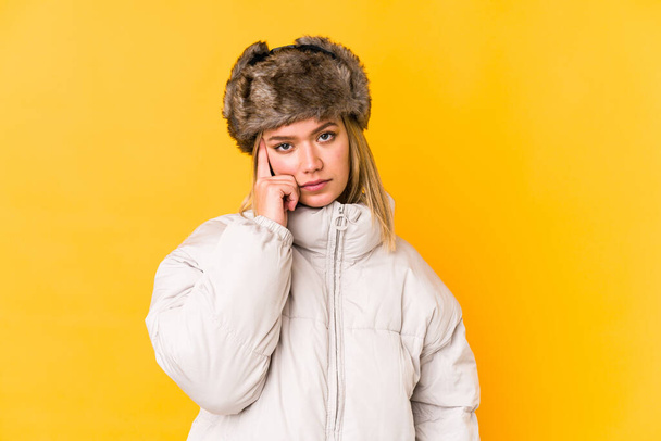 Young blonde woman wearing a winter clothes isolated Young blonde woman isolated on yellow background pointing temple with finger, thinking, focused on a task. - Foto, Imagem