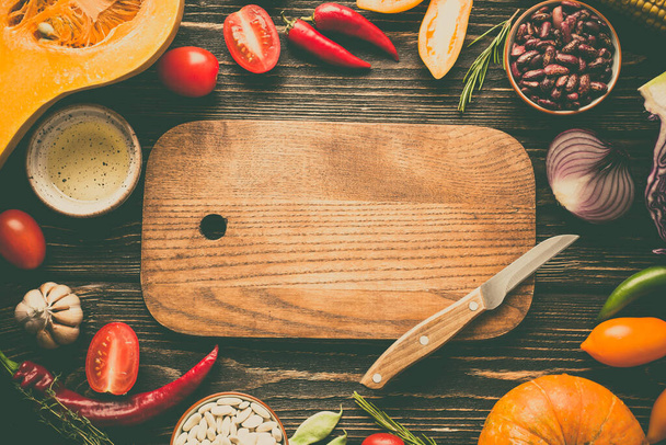 Продовольственная рамка. Свежие овощи и режущая доска на деревянном фоне. Копировать специи - Фото, изображение