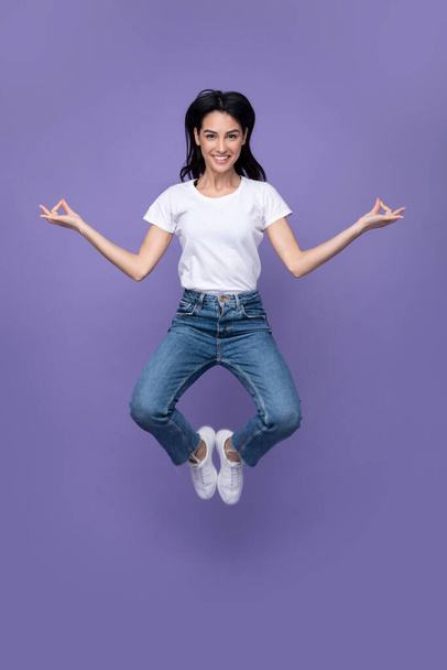 Young Lady Jumping Meditating In Mid-Air Posing Over Purple Background - Fotoğraf, Görsel