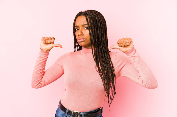 Young african american woman isolated on a pink background feels proud and self confident, example to follow. - Фото, зображення