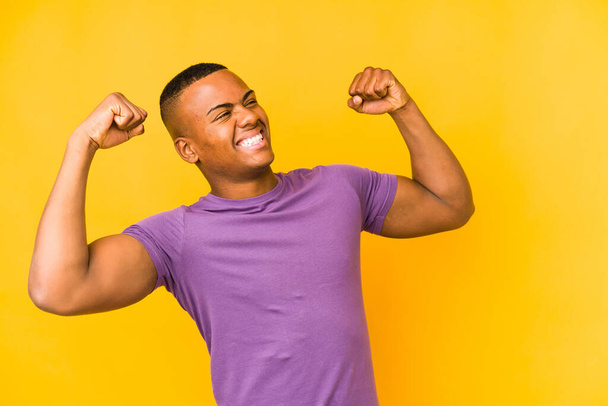 Young latin man isolated on yellow background raising fist after a victory, winner concept. - Fotografie, Obrázek