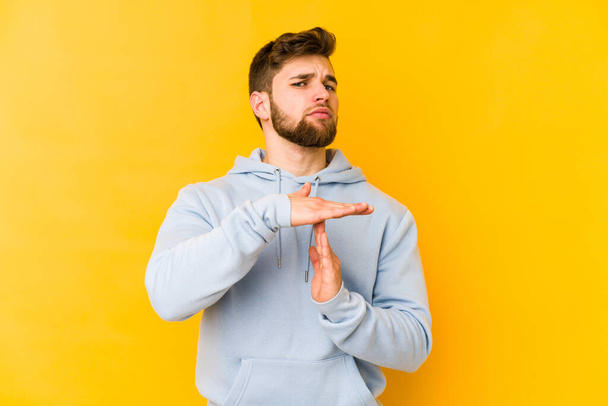 Young caucasian man isolated on yellow background showing a timeout gesture. - Photo, Image