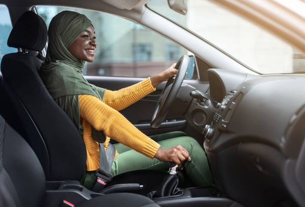 Portret szczęśliwej afrykańskiej muzułmanki w chustce w nowym samochodzie - Zdjęcie, obraz